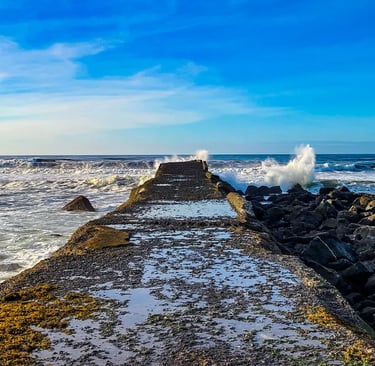 Oregon Coast - A pier jetty next to the lighthouse at a beach in Bandon