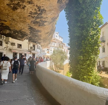 Tourists walk through Setenil de las Bodegas, a Spanish town with white houses built into cliffs.