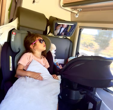 un enfant en train de dormir dans un siège auto à coté d'un bébé également dans un siège auto