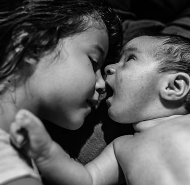 a baby is kissing her sister's face