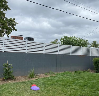 Horizontal vinyl picket fencing on top of block wall.