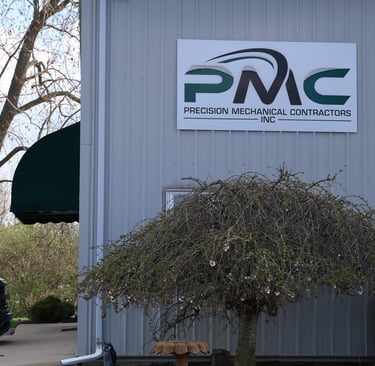 Exterior of Precision Mechanical Contractors Inc building with signage and landscaping.