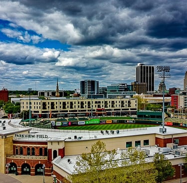 Parkview Field minor league baseball stadium in downtown Fort Wayne, Indiana under a dramatic cloudy sky.