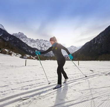 a woman in a black jacket and blue pants cross country skis