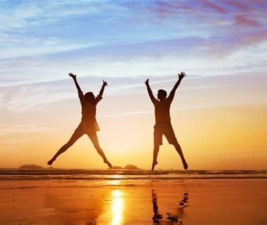 two joyful people jumping in the air at sunset