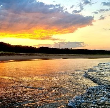 a sunset on a beach with waves crashing in the water