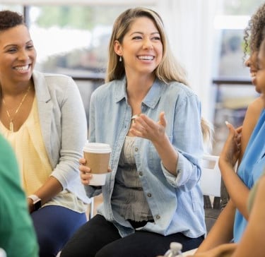 a group of people sitting around a table with coffee cups