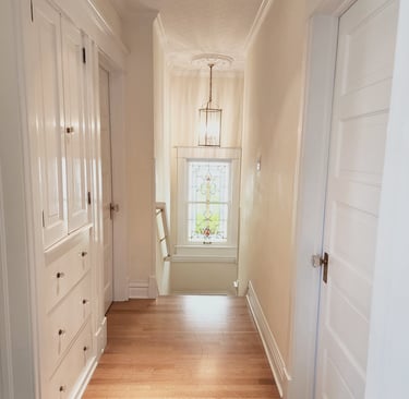 a hallway with white doors and a window, wood floors elegant interior hallway