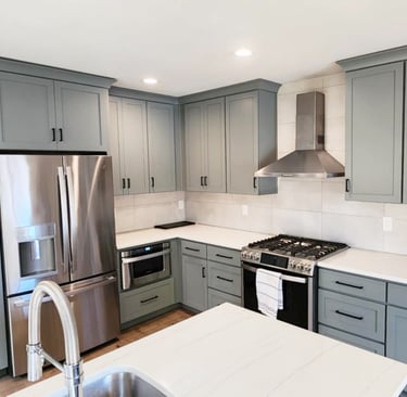 a kitchen with a stainless steel refrigerator and a stove top painted cabinets