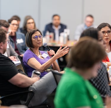 Leadership Austin participant speaks into a microphone during a thoughtful group discussion 