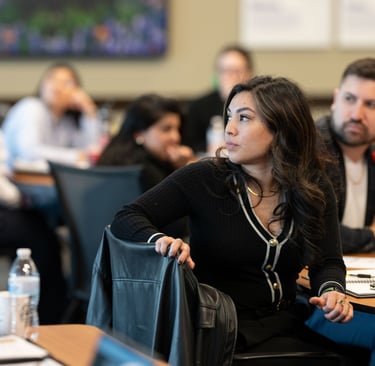 Jenny turns toward the speaker as Arnaldo listens behind her during Hispanic Austin Leadership class