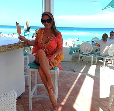 Wendy Corry, Flip Flop Cheers author & travel writer, photographed at a beach bar with champagne.
