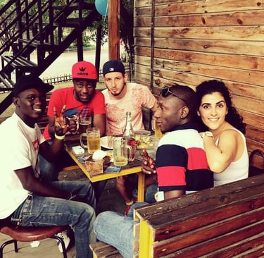 Diverse group of young friends smiling together while enjoying drinks at an outdoor bar.