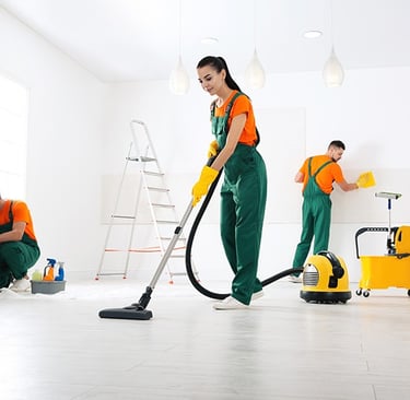 a woman in green overalls cleaning a room