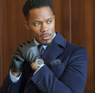 a man in a suit and gloves holding a watch