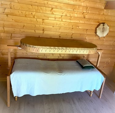 une table de soin au dessus un grand tambour chamanique . la personne s'allonge et ressent la vibrat