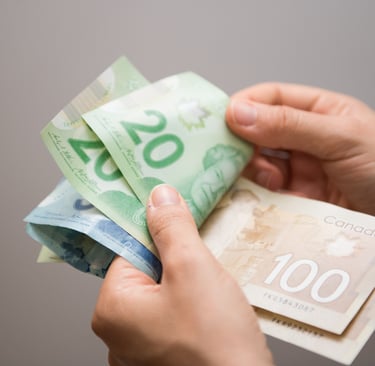 a person holding a stack of cash and a stack of Canadian dollarbills