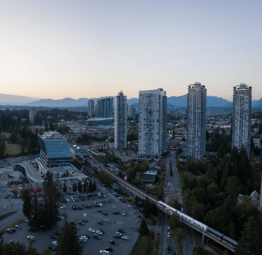 A train traveling through Surrey, BC with tall buildings