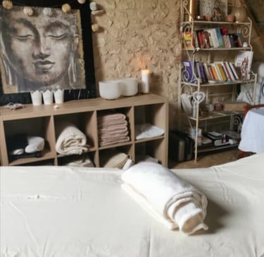une table de massage, des bougies, tête de bouddha, bols de cristal, serviettes et draps