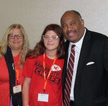 Dominic Carter at the Missouri Kinship Conference speaking with a teenager and her aunt who is raising her — highlighting fam