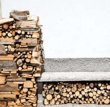 pile rangée de bûches avec un mur blanc en fond