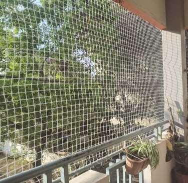 Installation team working together to secure a large safety net on a high-rise balcony.