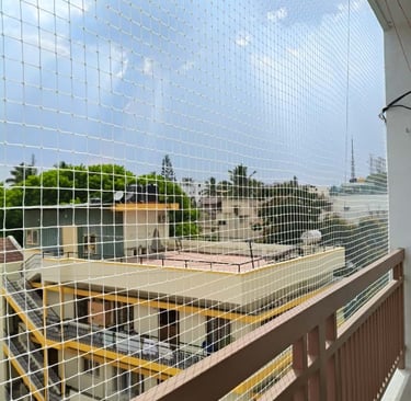Completed pigeon net installation on a residential balcony with a view of the Chennai skyline