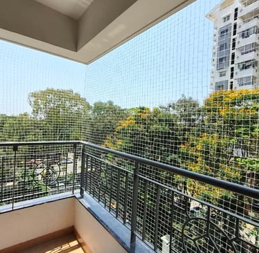 Technician carefully fitting a safety net frame on a balcony railing.