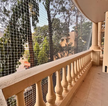 Wide shot of a modern apartment balcony fitted with Arjilli safety nets, showcasing pet safety featu