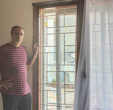 Bright balcony with mosquito nets installed on doors and windows, sunlight filtering through.