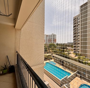 Elderly person enjoying fresh air on a balcony safely enclosed with sturdy safety nets.