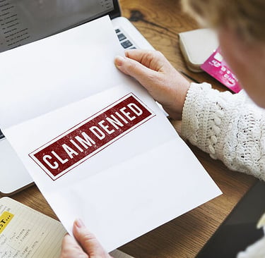 person looking at a denied insurance claim form