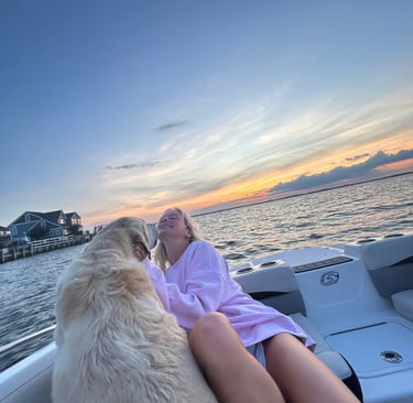 Whitney sitting on a boat with her dog, enjoying a peaceful moment on the water.