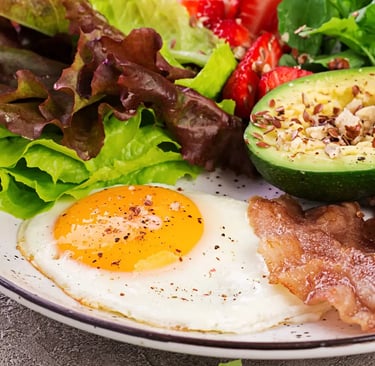 a plate of food with avocado, eggs, bacon, bacon, and