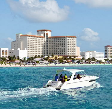 A convoy of clean, well-maintained cars driving along a coastal road with turquoise waters