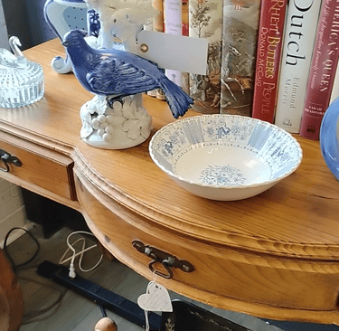 Antique store display with books, dishes, and a blue bird figurine, symbolizing old habits.