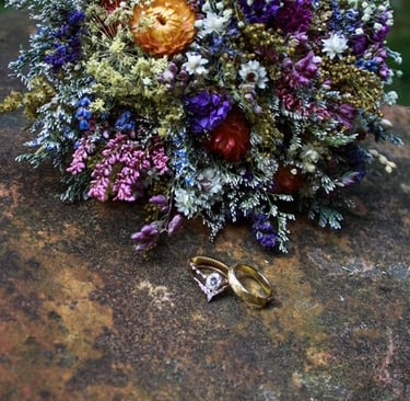 two rings and a bouquet of flowers on a stone