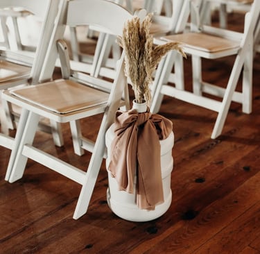 a vase of flowers in it next to rows of wooden chairs