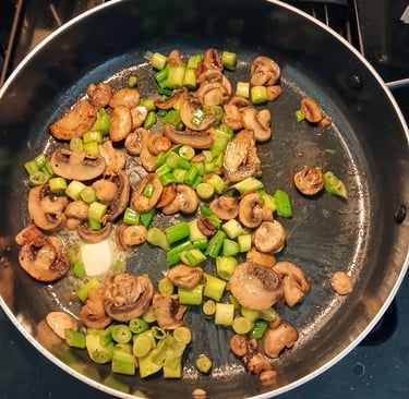 mushrooms and green onions cooking in a pan
