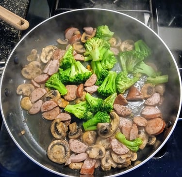 Sautéing mushrooms and sausage in a pan for alfredo pasta