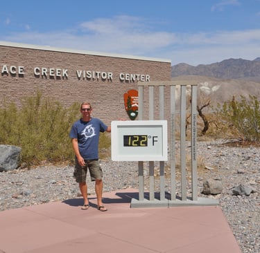 a man standing in front of a sign that says furnace creek, death valley