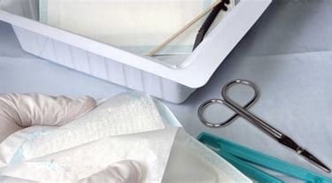 a person in a gloved gloved hand holding a pair of scissors and a