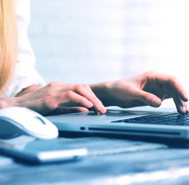Une femme blonde pianote sur le clavier de son ordinateur portable