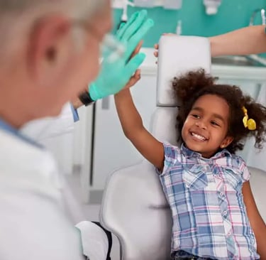 a child beating hands with pediatric dentist