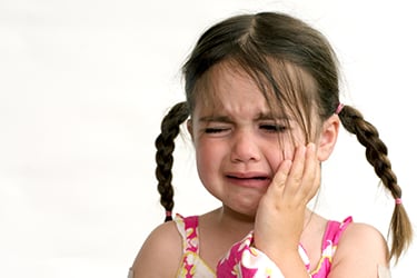 a child crying with keeping hands on cheeks dueto toothache