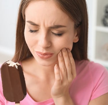 a person eating icecream experiencing pain due to sensitive teeth