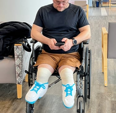 Person wearing handmade crocheted shoes sitting in a wheelchair at a doctor's office