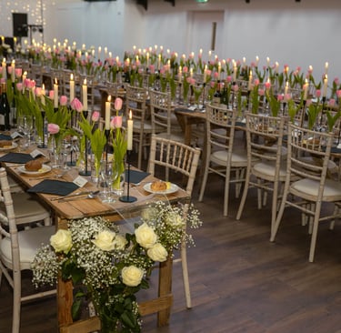 a long table with candles and flowers in a room