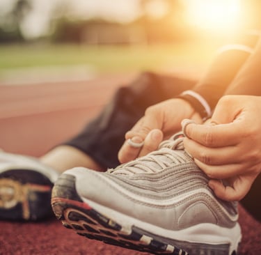 a person tieing their shoes at sunset on a track.