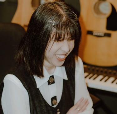 Ritchell Lim smiling with a guitar and keyboard in the background